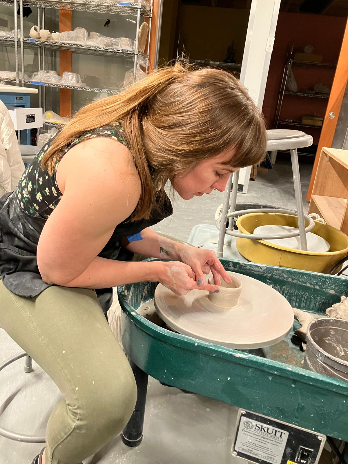 Mars deeply focused at the pottery wheel — hands in earth, fully present