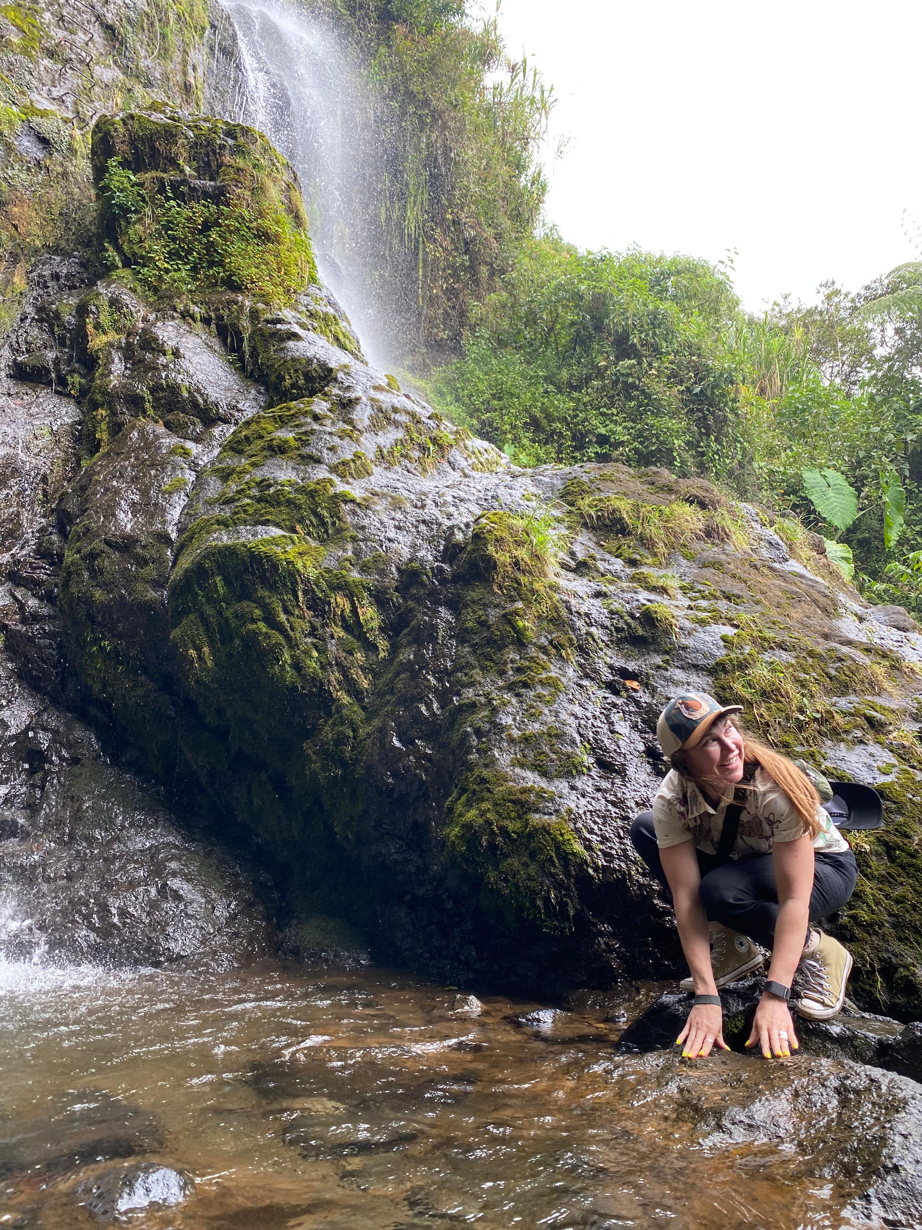 Mars crouching at a waterfall, looking up with wonder